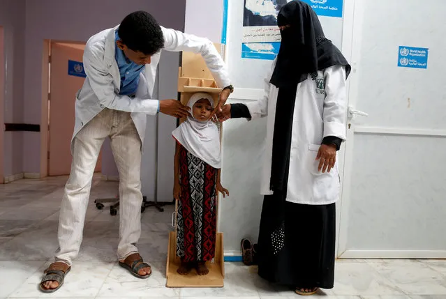 Nurses measure the height of Afaf Hussein, 10, who is malnourished, at a clinic in Aslam, in the northwestern province of Hajjah, Yemen, February 17, 2019. Afaf, who now weighs around 11 kg and is described by her doctor as “skin and bones”, has been left acutely malnourished by a limited diet during her growing years and suffering from hepatitis, likely caused by infected water. She left school two years ago because she got too weak. (Photo by Khaled Abdullah/Reuters)
