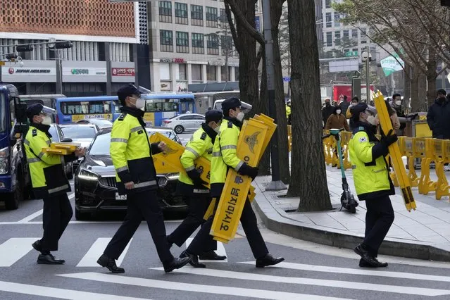 Police officers wearing face masks to help protect against the spread of the coronavirus carry barricades in Seoul, South Korea, Thursday, December 2, 2021. South Korea broke its daily record for coronavirus infections for a second straight day on Thursday with more than 5,200 new cases, as pressure mounted on a health care system grappling with rising hospitalizations and deaths. (Photo by Ahn Young-joon/AP Photo)