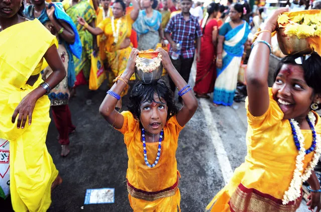 Indian Hindu children carry pots of milk during a religious procession for the Panguni Uthiram festival in Chennai on March 23, 2016. The festival is observed in the Tamil month of Panguni and is celebrated in honor of the Hindu God Murugan where devotees make offerings with sacrificial feats they believe will keep evil spirits away. (Photo by Arun Sankar/AFP Photo)