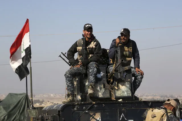 Two policemen sit atop of their armoured vehicle as Iraqi Federal police deploy after regaining control of the town of Abu Saif, west of Mosul, Iraq, Wednesday, February 22, 2017. (Photo by Khalid Mohammed/AP Photo)