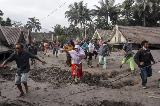 People inspect their village burried with volcanic ash from the Mount Semeru eruption at Sumber Wuluh village in Lumajang, East Java, Indonesia, 05 December 2021. The volcano erupted on 04 December leaving a number of people killed and missing. (Photo by Ammar/EPA/EFE)