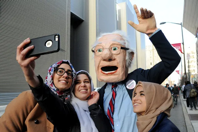 Wearing an oversized Bernie head, Dennis Meserole, poses for selfie with students in line to see Democratic presidential hopeful Bernie Sanders on Wednesday, April 6, 2016, at Temple University in Philadelphia. (Photo by Tom Gralish/The Philadelphia Inquirer via AP Photo)