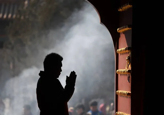 A man prays on the first day of the Tibetan New Year at the Yonghegong Lama Temple in Beijing on February 27, 2017. Tibetan New Year, known as Losar, is the most important festival in the Tibetan calendar. (Photo by Greg Baker/AFP Photo)
