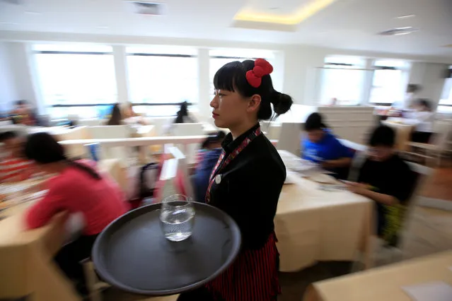 An employee carries a tray in China's first official Hello Kitty-themed restaurant in Shanghai, China, April 9, 2016. (Photo by Aly Song/Reuters)