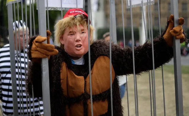 Man in a mask stands in a cage as people start to gather to demonstrate against the state visit of President Donald Trump in Parliament Square, central London, Tuesday, June 4, 2019. Trump will turn from pageantry to policy Tuesday as he joins British Prime Minister Theresa May for a day of talks likely to highlight fresh uncertainty in the allies' storied relationship. (Photo by Matt Dunham/AP Photo)