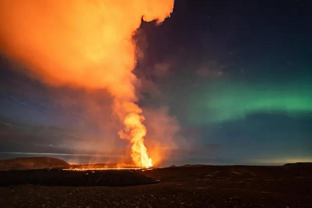 A view of the lava flowing from the volcano backdropped by the Northern Lights, near the town of Grindavik, Iceland, early Monday, March 25, 2024. (Photo by Marco di Marco/AP Photo)