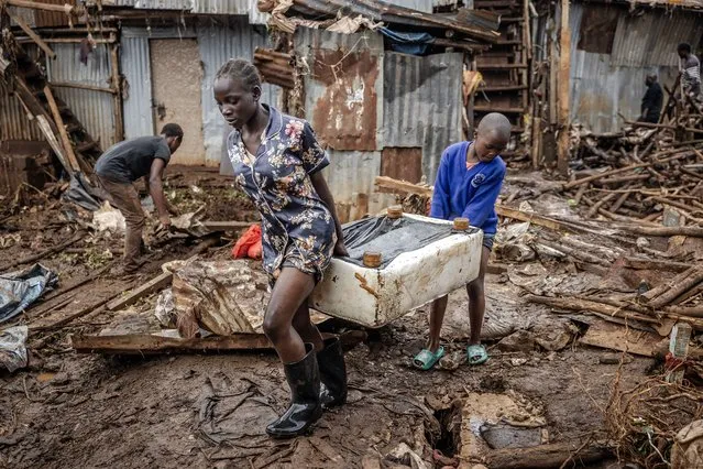 A girl and a boy carry a piece of furniture after visiting their house that was destroyed by floods following torrential rains at the Mathare informal settlement in Nairobi, on April 25, 2024. Torrential rains triggered floods and caused chaos across Kenya, blocking roads and bridges and engulfing homes in slum districts. The death toll from flash floods in Kenya's capital Nairobi has risen to 13 on April 25, 2024, police said. Kenyans have been warned to stay on alert, with the forecast for more heavy rains across the country in the coming days. (Photo by Luis Tato/AFP Photo)