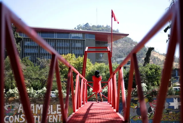 A woman stands at an urban intervention by chilean artist Ivan Navarro called “Rio de sangre” (Blood river), a tribute to the coronavirus disease (COVID-19) victims and in memory of the people that were thrown into the river before and during the Chilean dictatorship, during Santiago a Mil International Theatre Festival in Santiago, Chile, January 12, 2021. (Photo by Ivan Alvarado/Reuters)