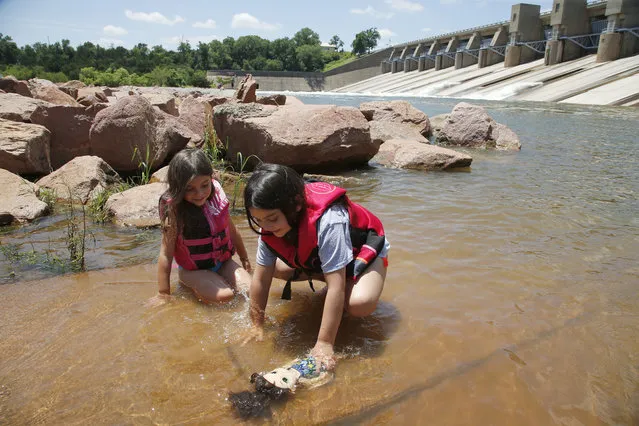 With Sandy Cove beach, campgrounds and boat ramps closed due to flooding, Kamee Sander, left, and Kyah Sander, right,  splash in the water beneath the dam at Canton Lake in Canton, Okla., Monday, July 1, 2019. The heavy rains that caused severe flooding in the central U.S. this spring also had the positive effect of lifting the Southern Plains out of a prolonged drought.  (Photo by Sue Ogrocki/AP Photo)