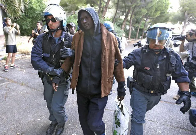 A migrant is evacuated by Italian police at the Franco-Italian border near Menton, southeastern France, Tuesday, June 16, 2015. Some 150 migrants, principally from Eritrea and Sudan, have been trying since last Friday to cross the border from Italy but have been blocked by French and Italian police. (AP Photo/Lionel Cironneau)