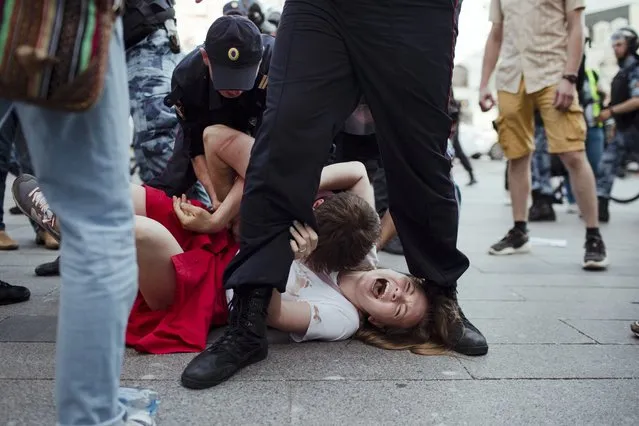 In this photo taken on Saturday, July 27, 2019, Inga Kudracheva screams as her boyfriend Boris Kantorovich lies atop her while police try to detain him during an unsanctioned protest in Moscow. Images of the young couple have been spread on social media. They say the crackdown by police has left them shaken but with their resolve strengthened. “People are not afraid of police anymore. Even though police were beating us violently and tried to intimidate us, it was worth it”, Kantorovich said. (Photo by Denis Sinyakov/AP Photo)