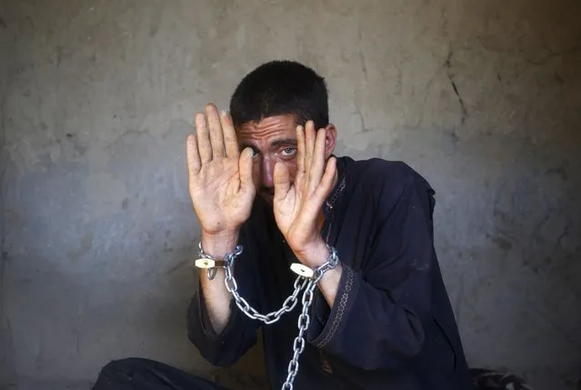 An Afghan man who is said to be suffering from mental health problems is chained in a mud room at the Mia Ali Baba shrine, in Jalalabad province, April 14, 2014. Residents in the area believe that spending 40 days chained in isolation at the shrine can cure mental health problems. (Photo by Reuters/Parwiz)