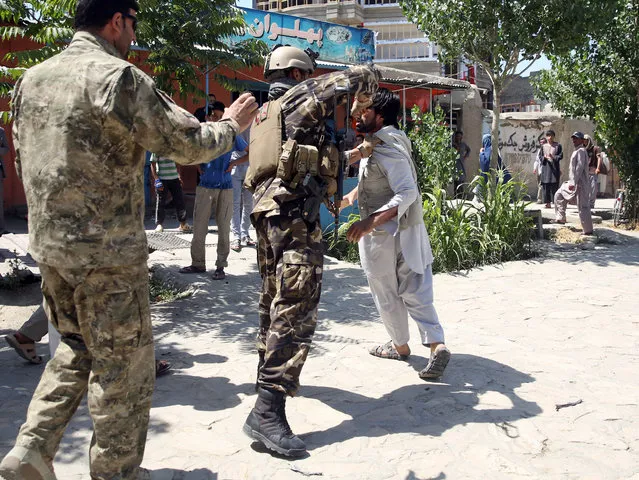 An Afghan soldier beats a man at the site of a suicide car bomb attack on a NATO convoy in Kabul, Afghanistan, Tuesday, June 30, 2015. An eyewitness said the man was later released. (Photo by Massoud Hossaini/AP Photo)