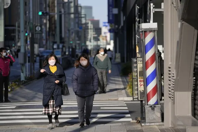 Women wearing face masks walk along the sidewalk in Tokyo, Wednesday, February 9, 2022. (Photo by Hiro Komae/AP Photo)