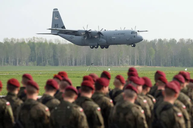 Members of a Polish paratrooper unit watch as a U.S. Air Force plane ferrying men and equipment of the U.S. Army 173rd Airborne Brigade lands at a Polish air force base on April 23, 2014 in Swidwin, Poland. Approximately 150 U.S. troops, as well as another 450 destined for the three Baltic states in coming days, will participate in bilateral military exercises over the coming weeks in a sign of commitment among NATO members. (Photo by Sean Gallup/Getty Images)