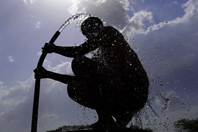 A man is silhouetted against the sun as he bathes on a hot summer day at a village on the outskirts of Ajmer on June 11, 2024 amid heatwave. India's heatwave is the longest ever to hit the country, the government's top weather expert said on June 10 as he warned people will face increasingly oppressive temperatures. Parts of northern India have been gripped by a heatwave since mid-May, with temperatures soaring over 45 degrees Celsius (113 degrees Fahrenheit). (Photo by Himanshu Sharma/AFP Photo)