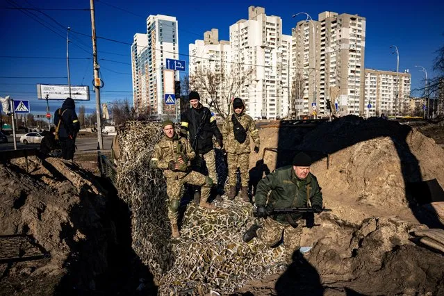 Kyiv residents and volunteers stand on top of APC while they prepare a rear post with trenches in Kyiv on February 28, 2022. Kyiv woke up from a 36-hour military curfew – enforced by shoot-on-sight orders – on Monday to prepare for the stalled Russian push on the Ukrainian capital. The Western-backed government's battled-hardened soldiers are stretched to the limit at the front. They are fighting Russia's well-armed forces near the Belarusian border in the north and Kremlin-annexed Crimea in the south. (Photo by Dimitar Dilkoff/AFP Photo)