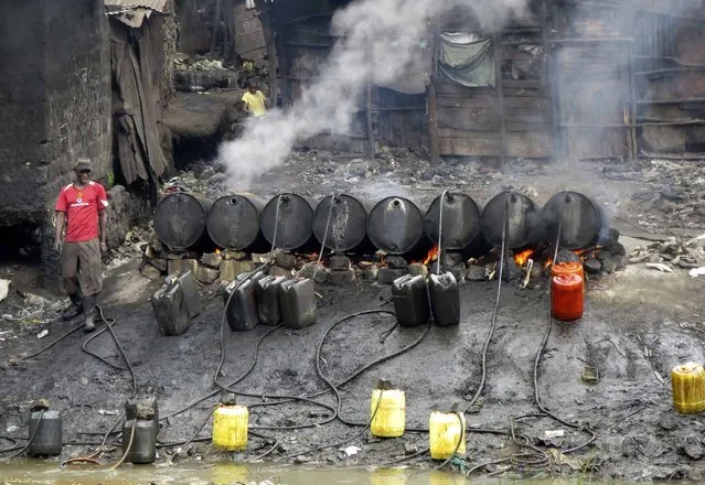 A labourer prepares distilled traditional brewed alcoholic liquor, locally known as “chang'aa”, at an illegal micro-brewery along a river in the suburbs of Kenya's capital Nairobi May 9, 2014. Eighty people have died after drinking from a batch of illegal liquor in Kenya and police have detained several people for questioning, officials and police said on Wednesday. (Photo by Thomas Mukoya/Reuters)
