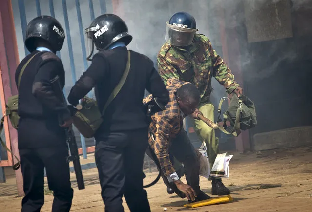 An opposition supporter is beaten with a wooden club by riot police as he tries to flee, during a protest in downtown Nairobi, Kenya Monday, May 16, 2016. (Photo by Ben Curtis/AP Photo)