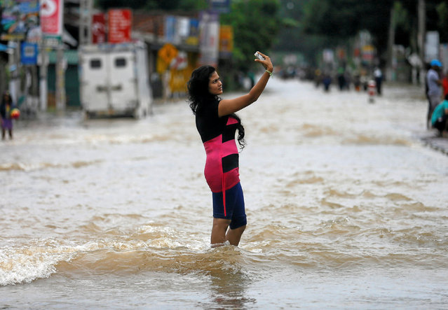 A woman takes a selfie while standing on a flooded road in Biyagama, Sri Lanka May 17, 2016. (Photo by Dinuka Liyanawatte/Reuters)