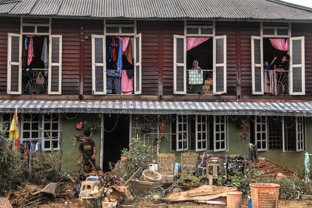 A kid (below,L) throws a rubbish as his relative reacts from first floor of their damaged house after the flooding a day earlier at Kuala Langat, 15KM from Kuala Lumpur, Malaysia, 20 December 2021. Several Malaysian states has been struck by floods caused by two days of heavy rain leaving five killed and 61,000 of residents to be evacuated with many trapped in their vehicles and homes. (Photo by Fazry Ismail/EPA/EFE/Rex Features/Shutterstock)