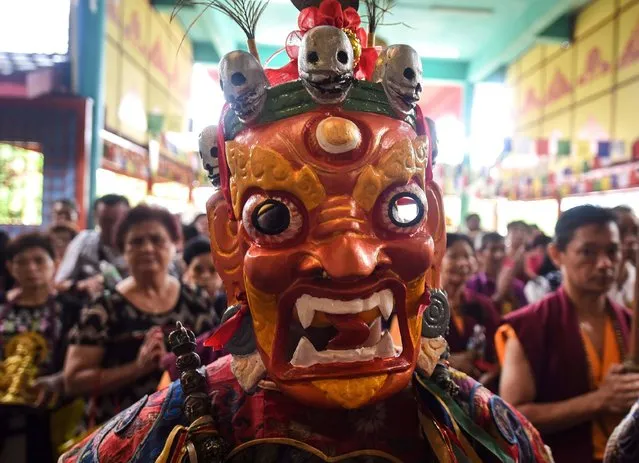A Buddhist priest wearing traditional costume performs rituals along with other devotees during Wesak day or Buddha Day festival celebrations at the Enlightened Heart Tibetan Buddhist temple in Ipoh on May 21, 2016. Wesak or Vesak festival is the most important Buddhist festival of the year as it commemorates the birth, enlightenment (nirvana), and death (Parinirvana) of Gautama Buddha. (Photo by Manan Vatsyayana/AFP Photo)