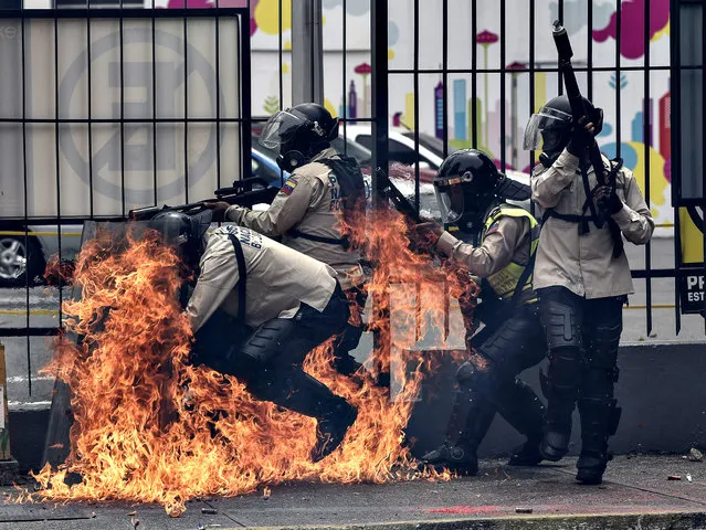 A group of riot policemen are hit by a Molotov cocktail hurled by an opposition demonstrator during a protest against President Nicolas Maduro, in Caracas on May 8, 2017. Venezuela' s opposition mobilized Monday in fresh street protests against President Nicolas Maduro' s efforts to reform the constitution in a deadly political crisis. Supporters of the opposition Democratic Unity Roundtable (MUD) gathered in eastern Caracas to march to the education ministry under the slogan “No to the dictatorship”. (Photo by  Carlos Becerra/AFP Photo)
