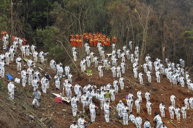 In this photo released by Xinhua News Agency, search and rescue workers pause for a three-minute moment of silence for the 132 people killed at the China Eastern flight crash site in Tengxian County on Sunday, March 27, 2022, in southern China's Guangxi Zhuang Autonomous Region. The second “black box” from a China Eastern Boeing 737-800 was found Sunday, raising hopes that it might shed light on why the passenger plane nosedived into a remote mountainous area in southern China last week, killing all 132 people on board. (Photo by Huang Xiaobang/Xinhua via AP Photo)