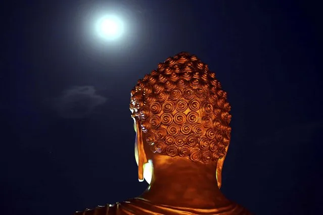 A full moon is seen behind a Buddha statue lit up on the eve of the Buddha Jayanti festival at a monastery in Bhopal, India, on May 13, 2014. The festival marks Buddha's birth, enlightenment and death. (Photo by Rajeev Gupta/Associated Press)