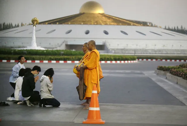 Buddhists pray to monks inside the Wat Dhammakaya temple grounds in Pathum Thani province, Thailand, Thursday, February 16, 2017. Hundreds of police are carrying out a raid on the headquarters temple of a controversial Buddhist temple sect to detain its chief, a monk facing criminal charges including accepting $40 million in embezzled money. (Photo by Sakchai Lalit/AP Photo)