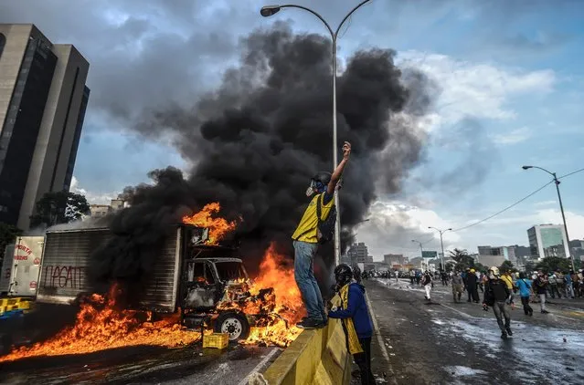 Anti-government protesters block the Francisco Fajardo highway in Caracas during a demonstration against Venezuelan President Nicolas Maduro on May 27, 2017. Demonstrations that got underway in late March have claimed the lives of 58 people, as opposition leaders seek to ramp up pressure on Venezuela's leftist president, whose already-low popularity has cratered amid ongoing shortages of food and medicines, among other economic woes. (Photo by Juan Barreto/AFP Photo)