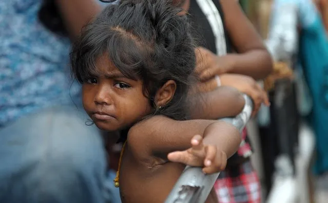 A young Sri Lankan flood victim looks on at a roadside camp in Kelaniya, on the outskirts of Colombo on May 22, 2016. Sri Lankan soldiers pulled more bodies from landslides and distributed food and water to hundreds of thousands of residents camped in shelters on May 22 after major floods hit the island. More than 80 people are known to have died so far across the island amid fears the number could rise – with 118 people still listed as missing. (Photo by Ishara S. Kodikara/AFP Photo)