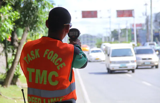 A traffic enforcer aims a speed limit machine to motorists in downtown district in Davao City in southern Philippines, Philippines December 18, 2013. (Photo by Lean Daval Jr./Reuters)