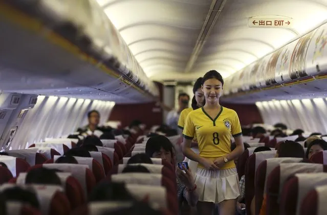 Flight attendants wearing Brazil soccer team jerseys walk along the aisle on an airplane travelling from Kunming to Hangzhou June 23, 2014. A Chinese airline company renovated the cabin of one of its flights then dressed the flight attendants with soccer jerseys as a way to celebrate the 2014 Brazil World Cup and hoping to attract more customers, local media reported. (Photo by Wong Campion/Reuters)