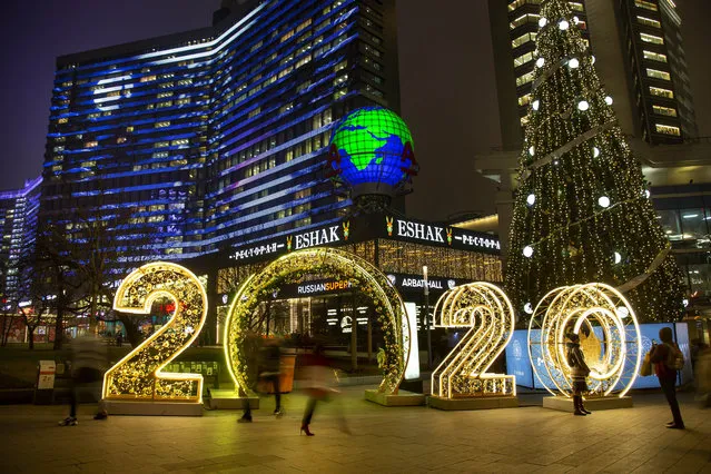 People walk in front of 2020 numbers of the upcoming new year decorated for Christmas and New Year celebrations in Novy Arbat street in Moscow, Russia, Wednesday, December 25, 2019. (Photo by Alexander Zemlianichenko/AP Photo)