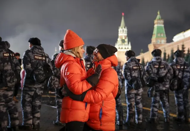 A couple share a tender moment during New Year's celebrations in Red Square with the Spasskaya Tower, second right, in the background in Moscow, Russia, Wednesday, January 1, 2020. Russians began the world's longest continuous New Year's Eve with fireworks and a message from President Vladimir Putin urging them to work together in the coming year. (Photo by Denis Tyrin/AP Photo)