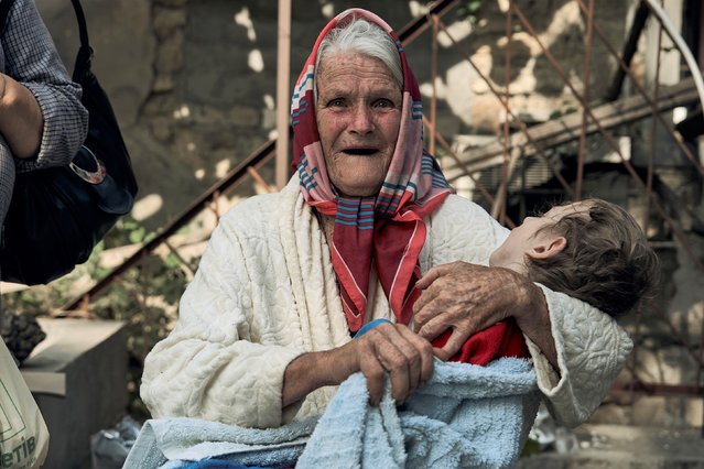 An elderly woman holds a disabled relative as they are evacuated from a flooded neighbourhood in Kherson, Ukraine, Thursday, June 8, 2023. Floodwaters from a collapsed dam kept rising in southern Ukraine on Thursday, forcing hundreds of people to flee their homes in a major emergency operation that brought a dramatic new dimension to the war with Russia, now in its 16th month. (Photo by Libkos/AP Photo)