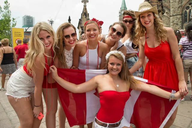 (from left) Meghan McMann, Frederique Duquette, Laura Castillani, Olivia Allen, Taylor Olson, Madison Skot-Niki, and Chloe Hutchison (centre with flag) having fun dressed in read and white as people flock to Parliament Hill and the downtown core to enjoy Canada's 147th birthday. Photo taken at 13:06 on July 1, 2014. (Photo by Wayne Cuddington/Ottawa Citizen)