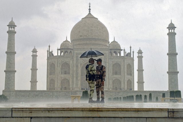 Soldiers hold an umbrella as they stand guard at the Taj Mahal, amid rainfall in Agra on August 6, 2024. (Photo by Pawan Sharma/AFP Photo)