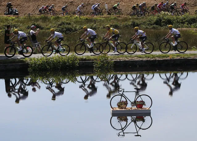 Britain's Geraint Thomas, wearing the overall leader's yellow jersey, and new overall leader Britain's Chris Froome, left of Thomas, are reflected in a pond as they ride in the pack during the fifth stage of the Tour de France cycling race over 160.5 kilometers (99.7 miles) with start in Vittel and finish in La Planche des Belles Filles, France, Wednesday, July 5, 2017. (Photo by Christophe Ena/AP Photo)