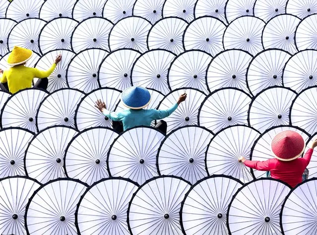 Workers lay out hundreds of umbrellas in neat lines ready for painting on May 26, 2022. The parasols are handmade using thick paper in Bogor, West Java, Indonesia. (Photo by Lisdiyanto Suhardjo/Solent News)