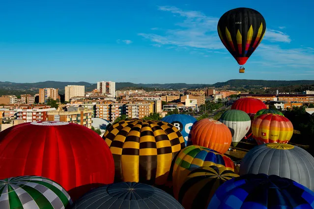 A Hot air balloons flies over Igualada during an early flight as part of the European Balloon Festival on July 10, 2014 in Igualada, Spain. The early morning flight of over 30 balloons was shorter than expected due to windy weather. This flight is organised as a curtain raiser for the four-day European Balloon Festival. Now is the 18th year of the most important hot air Balloon event in Spain and one of the biggest in Europe. (Photo by David Ramos/Getty Images)