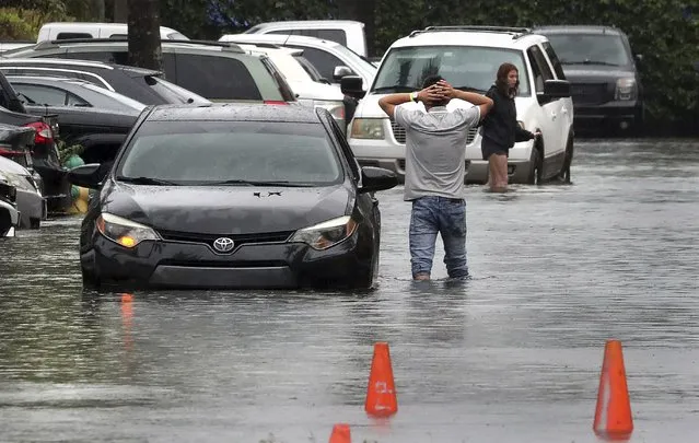 A driver climbs out of his stalled car after he tried to move it to higher ground from the flooded parking lot at the Beachwalk at Sheridan Apartments in Dania Beach, Fla., on Saturday, June 4, 2022. (Photo by Mike Stocker/South Florida Sun-Sentinel via AP Photo)