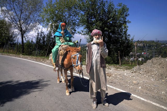 Ali Mohammad his wife Roshini, sitting on horseback, show the indelible ink mark on their index finger after casting their vote in Pehlipora, south of Srinagar, Indian controlled Kashmir, Wednesday, September 18, 2024. (Photo by Dar Yasin/AP Photo)