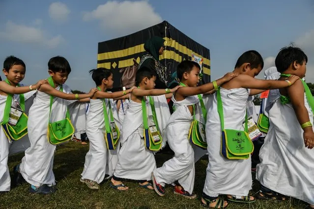 Ihram-clad Malaysian Muslim boys from the Little Caliphs kindergarten circumambulate a mockup of the Kaaba, Islam's most sacred structure located in the holy city of Mecca, during an educational simulation of the Hajj pilgrimage in Shah Alam, outside Kuala Lumpur on July 24, 2017. Thousands of Malaysian children took part in a practice run for the Muslim hajj pilgrimage on July 24, walking round a model of the holy Kaaba shrine under the tropical sun. The hajj is one of the five pillars of Islam, which capable Muslims must perform at least once, and marks the spiritual peak of their lives. (Photo by Mohd Rasfan/AFP Photo)