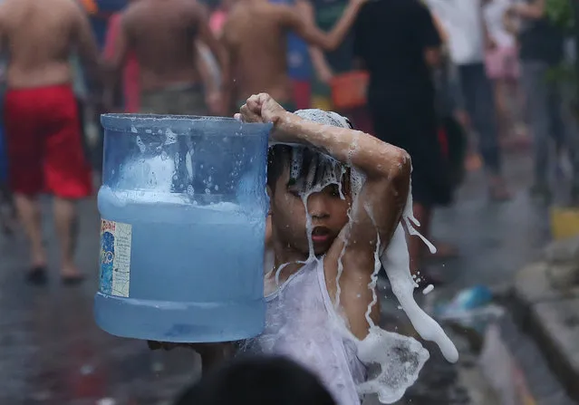 A Filipino boy carries a container with used water as he helps in controlling the fire that hit a residential area in suburban Quezon city, north of Manila, Philippines Tuesday, June 28, 2016. The fire gutted about 300 houses and left at least 600 families homeless said a Fire Officer. (Photo by Aaron Favila/AP Photo)