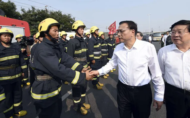 In this Sunday, August 16, 2015 photo released by China's Xinhua News Agency, Chinese Premier Li Keqiang, center right, visits fire fighters working at a massive blast site in Tianjin, north China. (Photo by Zhang Duo/Xinhua via AP Photo)