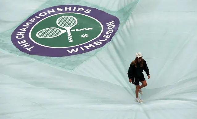 A member of the ground staff walks on the court cover, as rain delays play on day five of the Wimbledon Tennis Championships in London, Friday, July 1, 2016. (Photo by Ben Curtis/AP Photo)