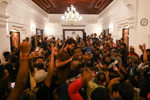 Demonstrators shout slogans and take selfies inside the office building of Sri Lanka's prime minister during an anti-government protest in Colombo on July 13, 2022. Thousands of anti-government protesters stormed into Sri Lanka Prime Minister Ranil Wickremesinghe's office on July 13, hours after he was named as acting president, witnesses said. (Photo by Arun Sankar/AFP Photo)