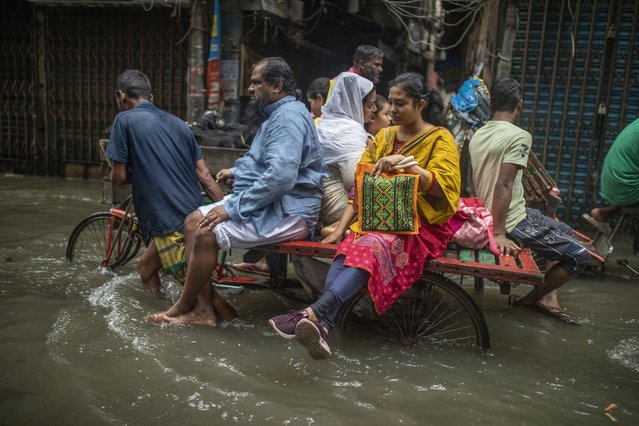 People sit on a rickshaw in a flooded street in the Alu Bazar area of Dhaka, Bangladesh, 03 October, 2024. (Photo by Monirul Alam/EPA/EFE)